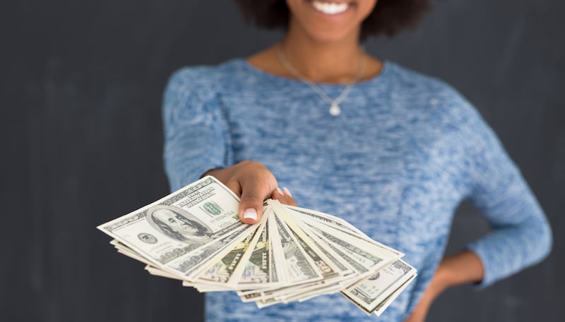 black woman holding money on gray background